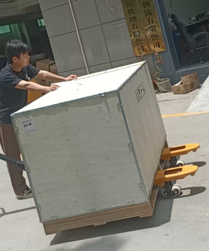 Crated oversized equipment being moved on a hand pallet jack at origin